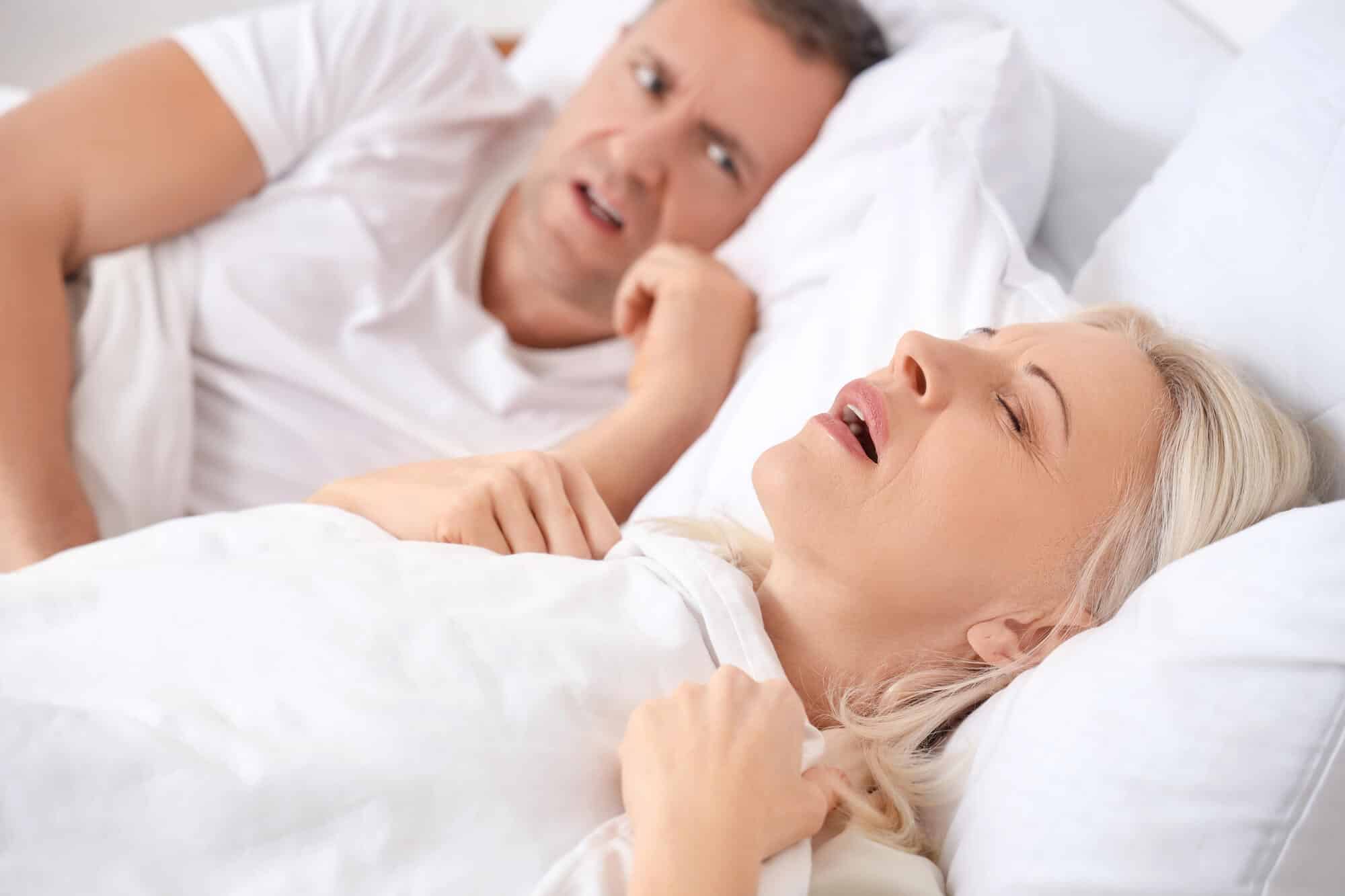 Woman snoring in bed, a common sign of sleep apnea