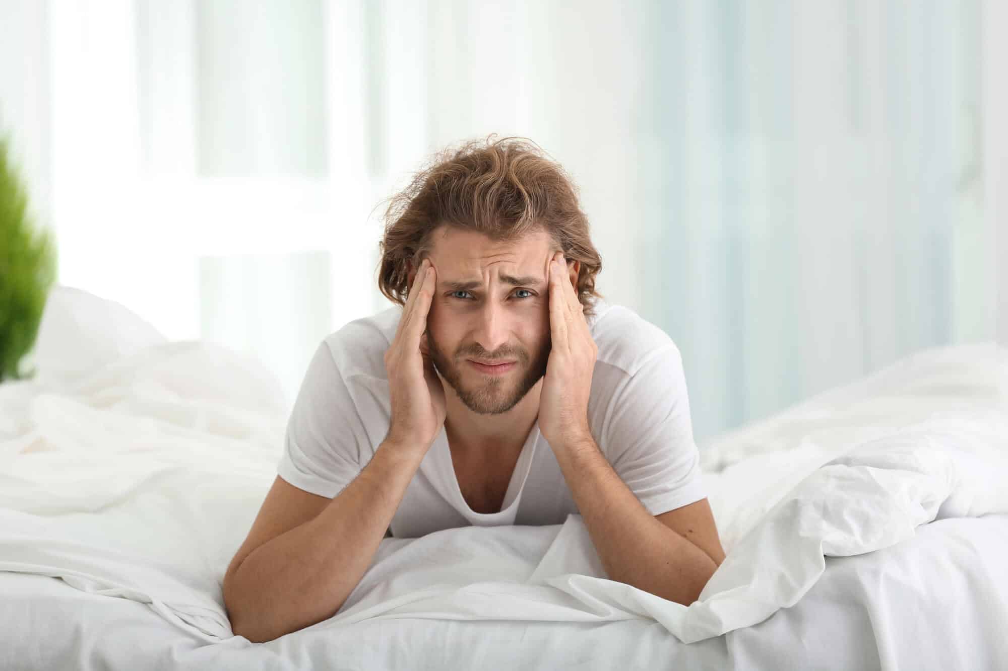 Man in bed looking exhausted from poor sleep caused by sleep apnea