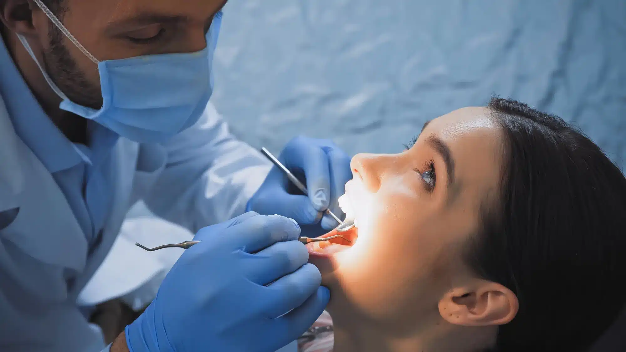 Dentist placing a filling on a patient's tooth with a dental light