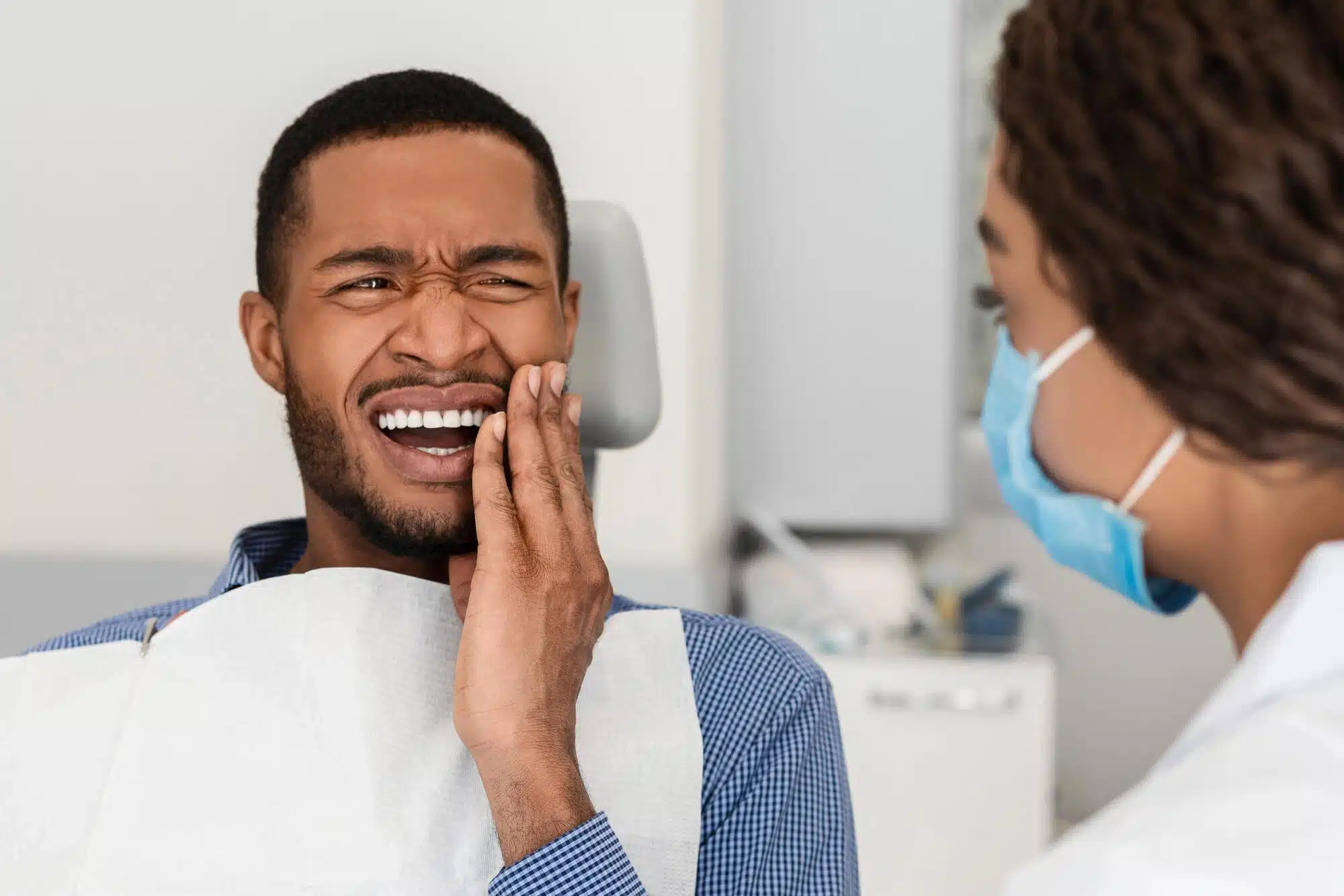 Patient holding his jaw in discomfort from teeth grinding at a dental visit