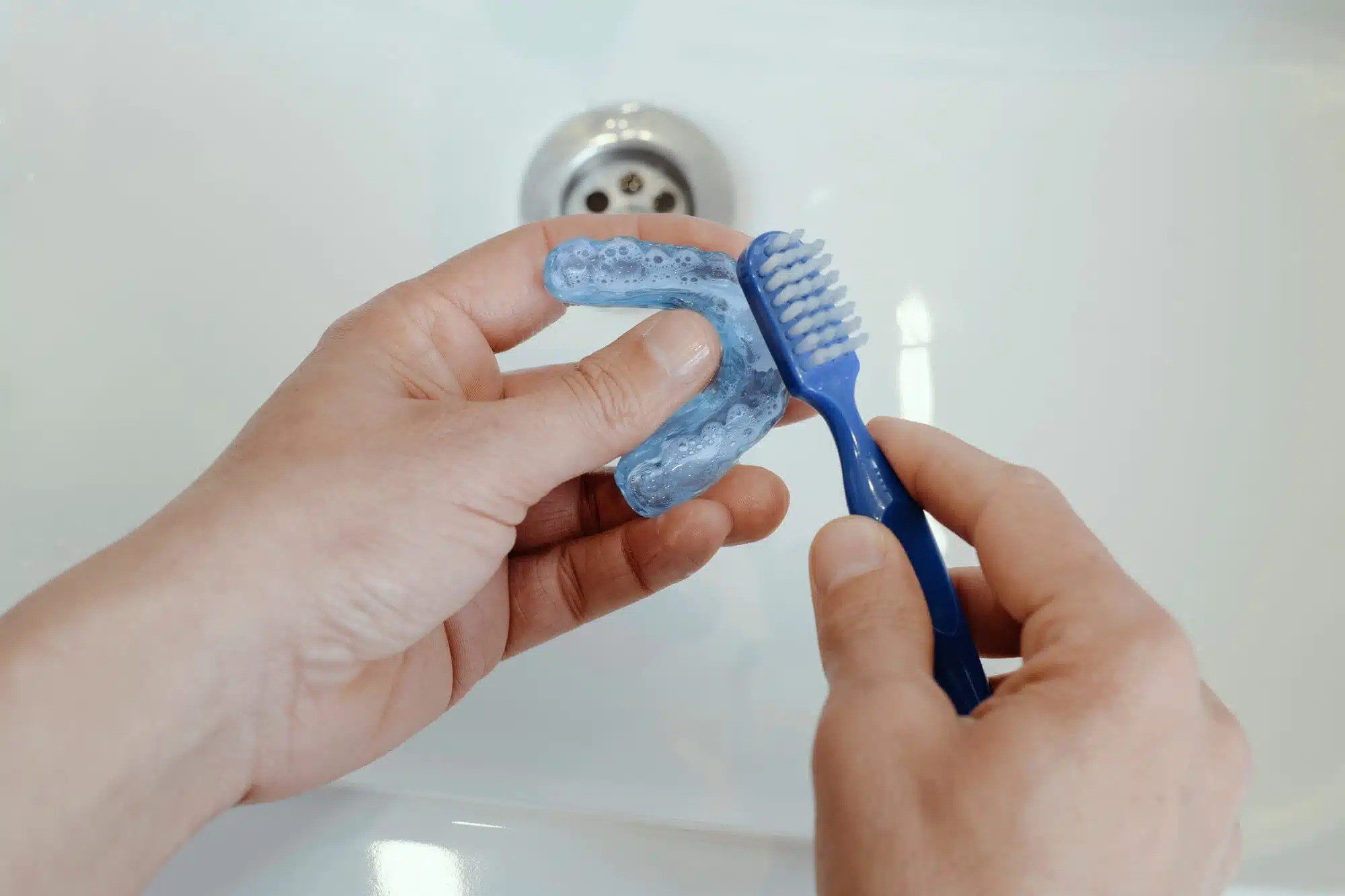 Cleaning a night guard with a soft toothbrush to help it last longer