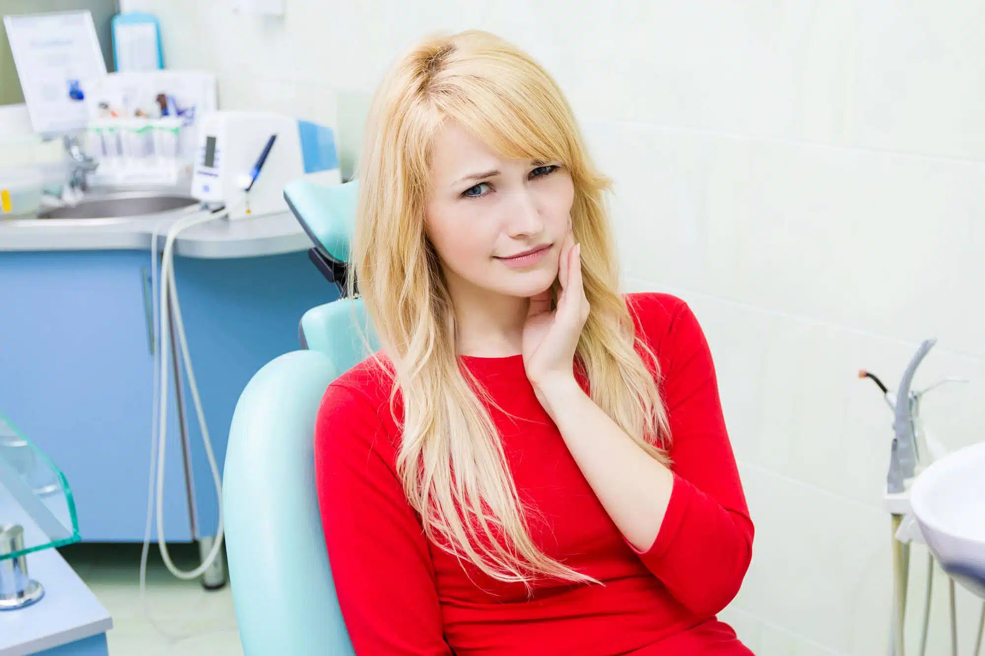 Woman with tooth pain in a dental chair, considering a tooth extraction