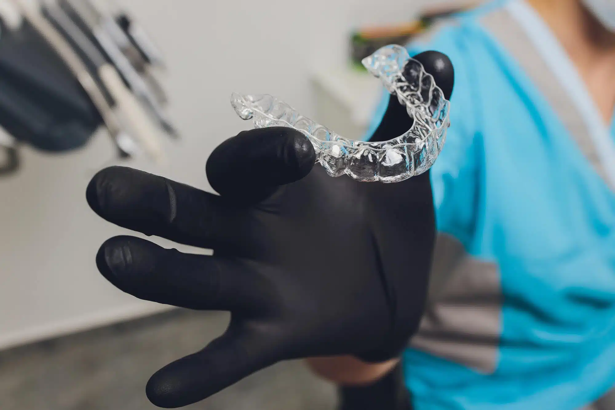 Clear Invisalign aligner held in a gloved hand