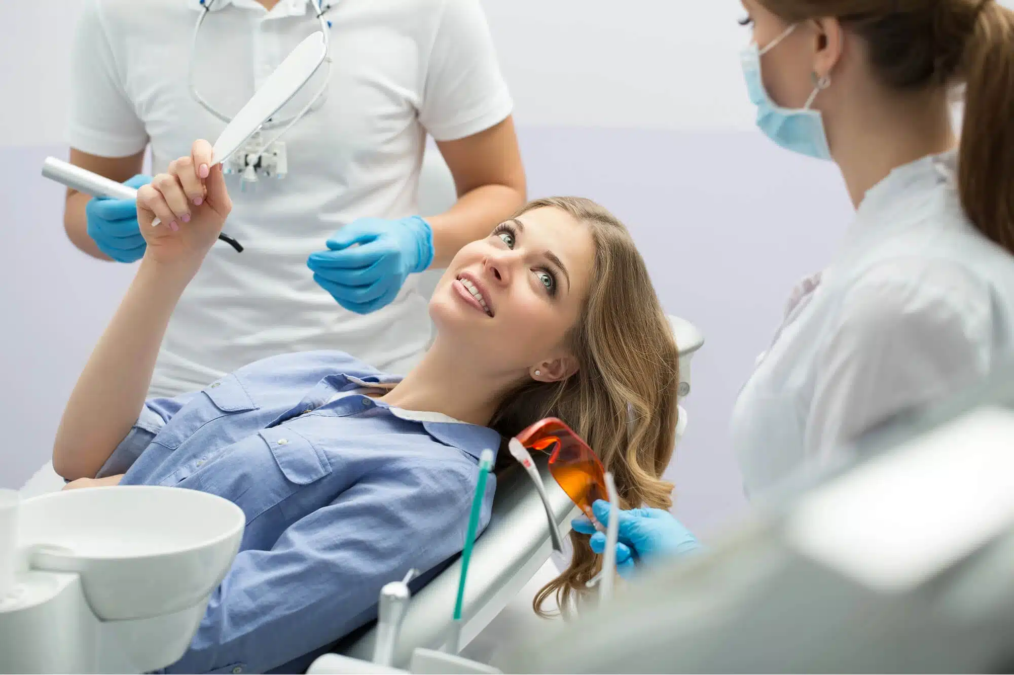 Woman smiling at her teeth in a mirror during an Invisalign visit