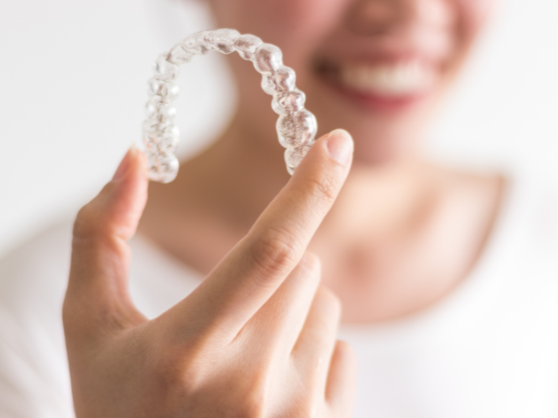 Adult woman holding an invisalign tray.
